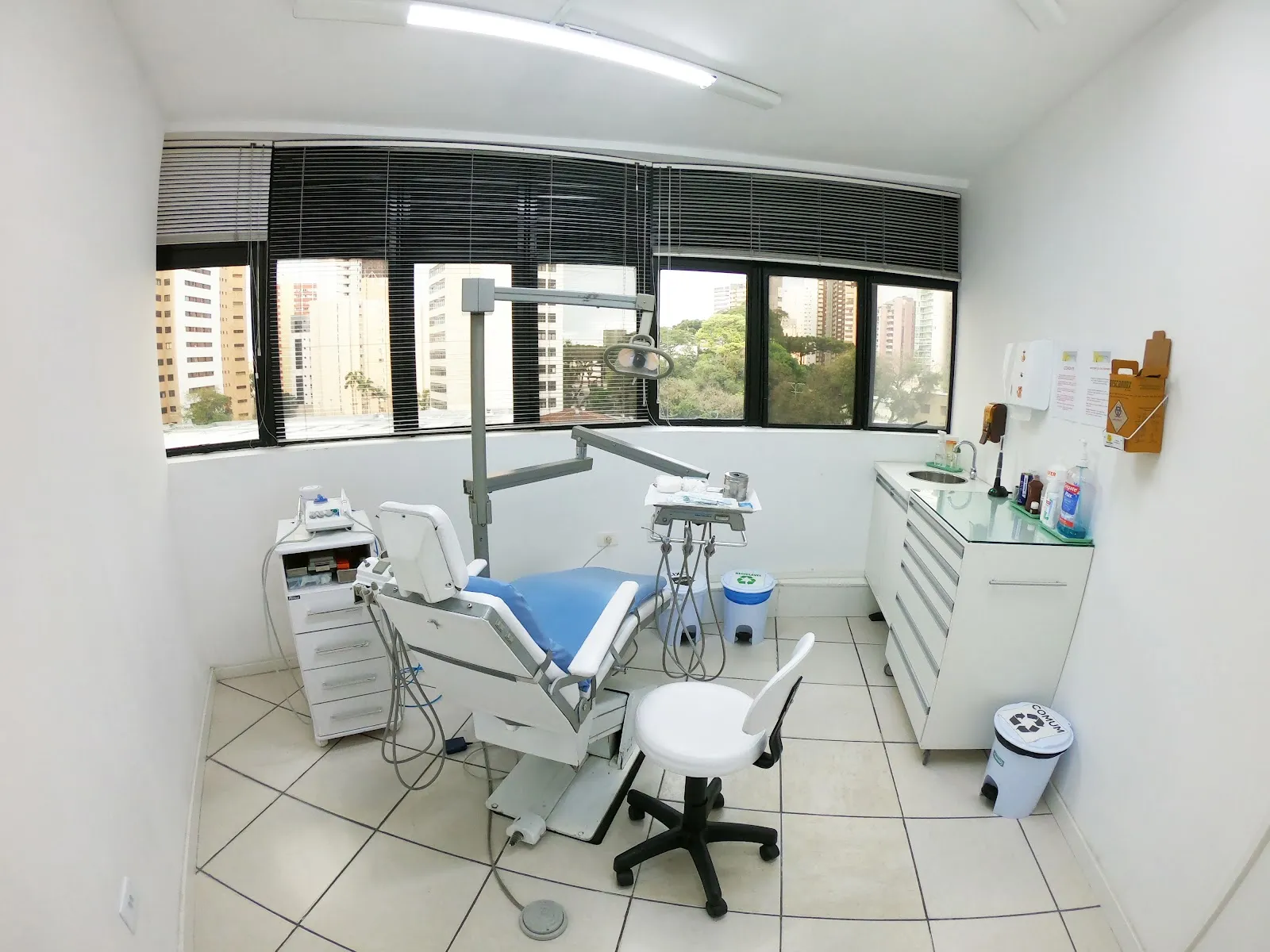 Consultório da clínica, com cadeira odontológica e janela para a cidade